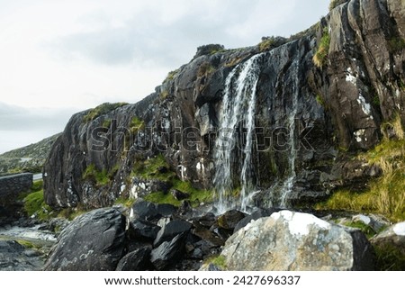 Small waterfall at the Conor Pass, one of the highest Irish mountain passes served by an asphalted road, located on the south-western end of the Dingle Peninsula, County Kerry, Ireland Royalty-Free Stock Photo #2427696337