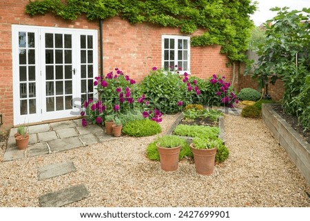 UK house and garden with patio and French doors. Cottage or courtyard garden (backyard) with gravel and York stone paving Royalty-Free Stock Photo #2427699901