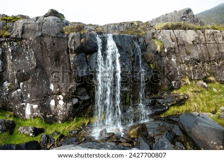 Small waterfall at the Conor Pass, one of the highest Irish mountain passes served by an asphalted road, located on the south-western end of the Dingle Peninsula, County Kerry, Ireland Royalty-Free Stock Photo #2427700807