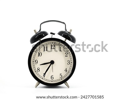 
A black alarm clock featuring two bells on top, chrome handle, and legs, captured against a pristine white background. 
 Royalty-Free Stock Photo #2427701585