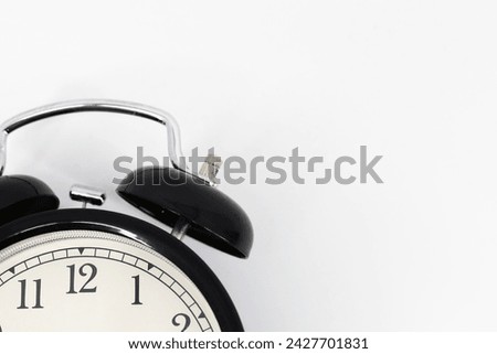 
A black alarm clock featuring two bells on top, chrome handle, and legs, captured against a pristine white background.  Royalty-Free Stock Photo #2427701831