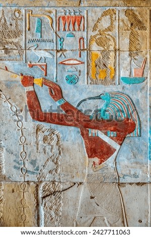 Carving with colorful hieroglyphs and Thoth with a ibis head, interior of Karnak temple in Luxor, Egypt. Thoth is the Egyptian god of writing, magic, wisdom, and the moon.