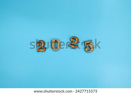 Wooden numbers 2025 on blue background. Planning goals and success concept.