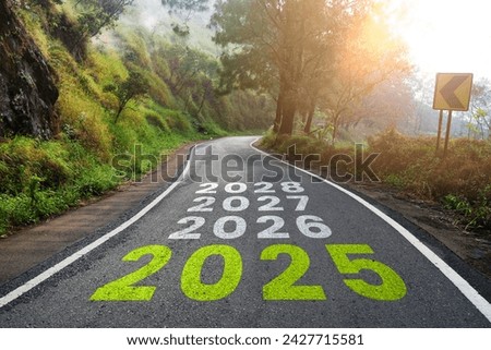 New year 2025 or straight road concept. Text 2025, 2026, 2027 written on the road in the middle of the asphalt road at sunset. Concept of planning, goals, challenges, new year resolutions. Royalty-Free Stock Photo #2427715581