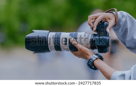 Man with camera and a big telephoto lens. Photographer outdoors with big zoom digital lens as professional equipment getting ready take a photo. Selective focus.