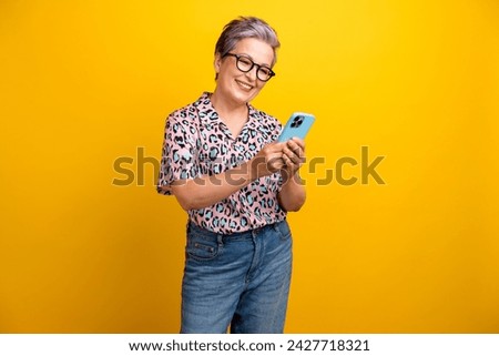 Photo portrait of pretty retired female hold device read news eshop wear trendy leopard print outfit isolated on yellow color background