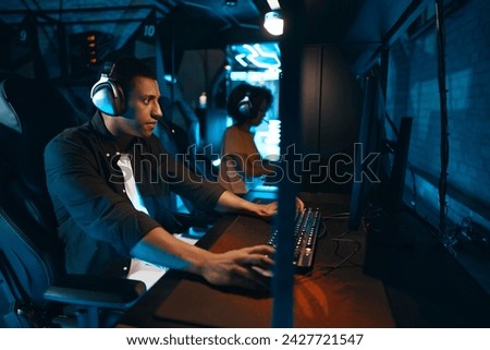 A man in headphones sits at a computer and actively reacts to the game. High quality photo