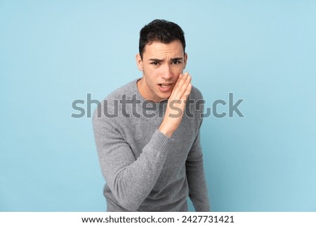 Young caucasian handsome man isolated on blue background whispering something Royalty-Free Stock Photo #2427731421