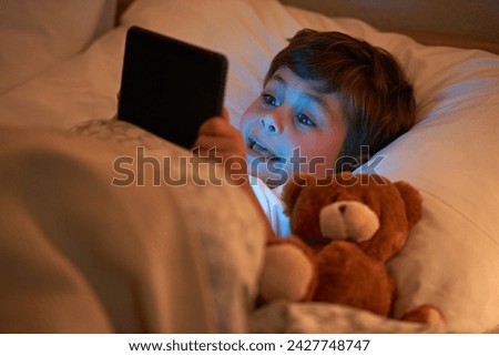 Boy, kid and tablet in bed at night with smile, reading or online game with app in family home. Child, bedroom and digital touchscreen for movie, cartoon and streaming subscription to relax in house