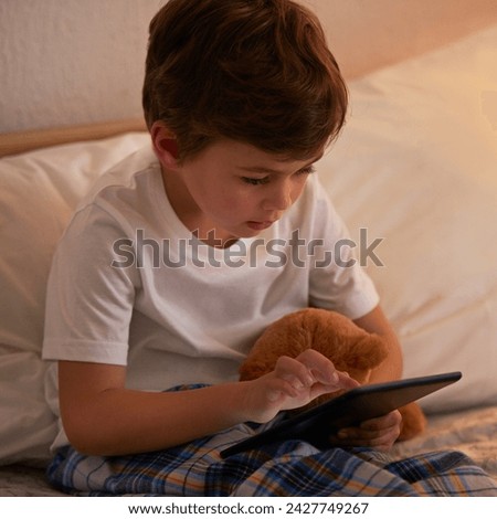 Boy, child and tablet in bed at night for typing, reading or online game with app in family home. Kid, bedroom and digital touchscreen for movie, cartoon and streaming subscription to relax in house