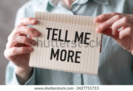 Tell Me More text on card in hands, concept background Royalty-Free Stock Photo #2427751713