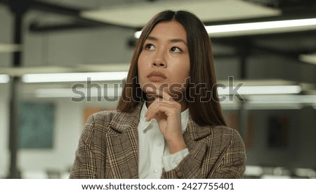 Asian girl in office Korean business woman lady Chinese businesswoman Japanese female manager worker student indoors confused pensive think thoughtful thinking puzzled solving challenge idea solution Royalty-Free Stock Photo #2427755401