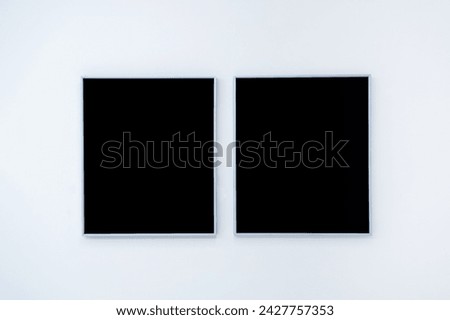 Mockup two blank space in black vertical square artist painting frames, isolated on white wall background. Empty 2 photo frames hanging on white wall in museum.