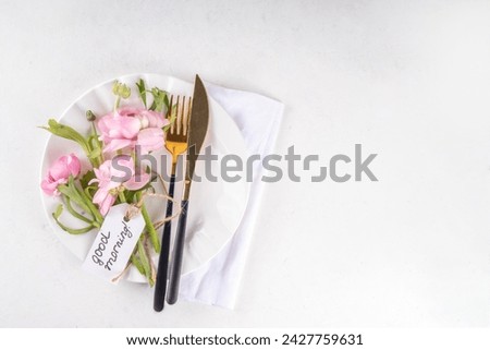 Spring holiday table setting with tender cute rose pink flowers, cutlery - plate, knife, fork on white background with tag Good morning, top view copy space