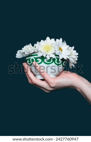 Female hand holding kazakh bowl piala with national ornament filled with blooming flowers. Photo on dark blue background. Pefrect photo for Nauryz greetings Royalty-Free Stock Photo #2427760947