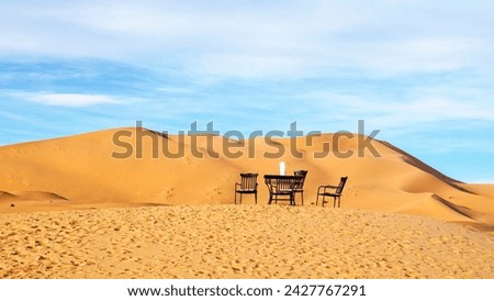 Classic chairs and table set in the dunes of the Moroccan desert, romantic and fantasy concept. Panoramica.