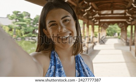 Confident hispanic woman, an all-smile beautiful brunette, enjoys taking a fun selfie at traditional japanese heian jingu shrine, kyoto.