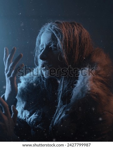 Fine-art portrait of a girl or woman who is frozen and covered in frost. The skin is covered with ice or snow. The clothes are covered with snow. The Snow Queen at winter. 