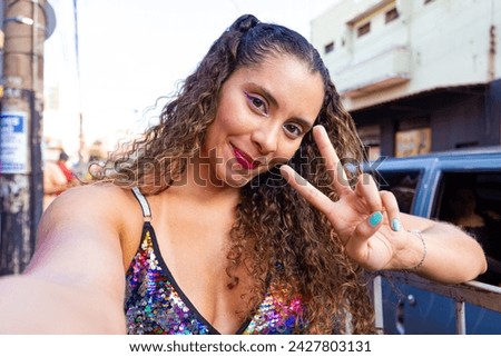 Young woman at a street carnival taking a selfie making a v sign with her hand
