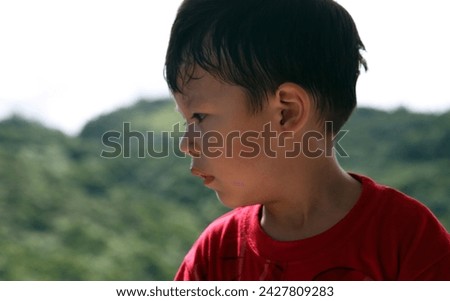 Exterior photo view portrait visual of a young eurasian asian handsome cute good looking kid chld children male boy who is happy during outdoor activities on summer time sunny weather