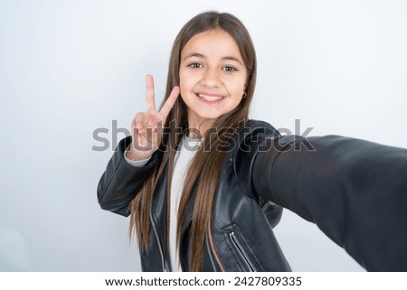 Positive Young beautiful teen girl wearing biker jacket take selfie make v-sign