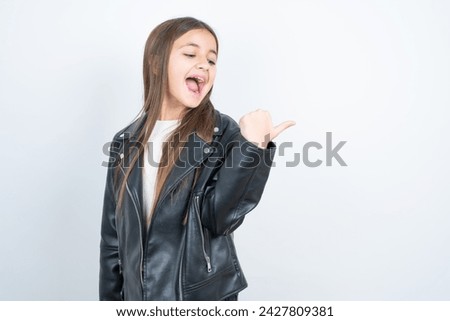 Impressed Young beautiful teen girl wearing biker jacket point back empty space