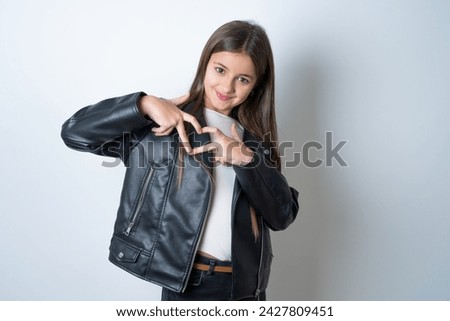 Serious Young beautiful teen girl wearing biker jacket keeps hands crossed stands in thoughtful pose concentrated somewhere