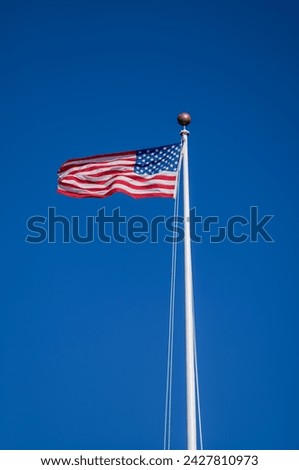 Red White, and Blue American Flag on a White Flagpole with a Cerulean Blue Sky Above.