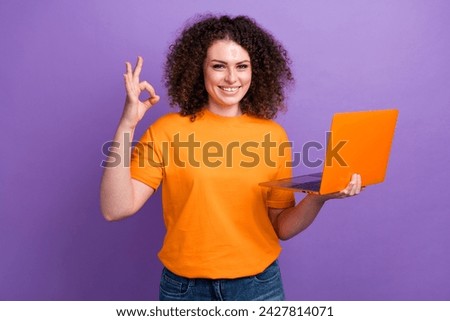 Photo of sweet confident lady dressed orange t-shirt showing okey gesture writing modern device isolated violet color background