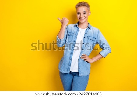 Photo portrait of lovely young lady point empty space billboard dressed stylish denim garment isolated on yellow color background