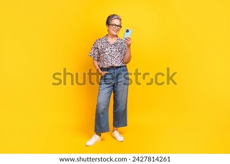 Full body photo of attractive pensioner woman hold gadget post dressed stylish leopard print clothes isolated on yellow color background