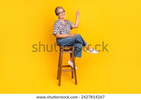 Full body photo of pensioner woman wooden chair point empty space dressed stylish leopard print clothes isolated on yellow color background