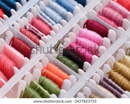 Bobbins with different colour embroidery threads in a plastic sorting box. Royalty-Free Stock Photo #2427823733