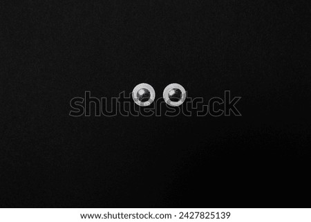 Close up of googly eyes on a black background with copy space