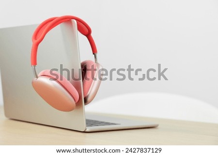 Modern laptop and headphones on wooden table. Space for text