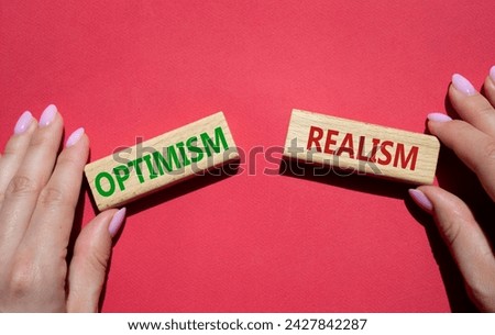Optimism or Realism symbol. Concept word Optimism or Realism on wooden blocks. Businessman hand. Beautiful red background. Business and Optimism or Realism concept. Copy space