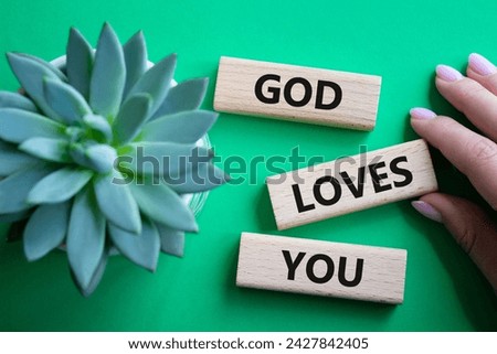 God loves you symbol. Wooden blocks with words God loves you. Beautiful green background with succulent plant. Prayer hand. Religion and God loves you concept. Copy space.