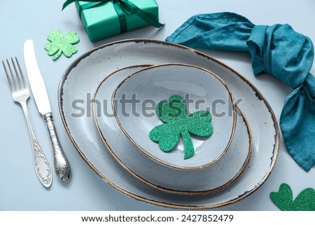 Beautiful table setting for St. Patrick's Day celebration on blue background
