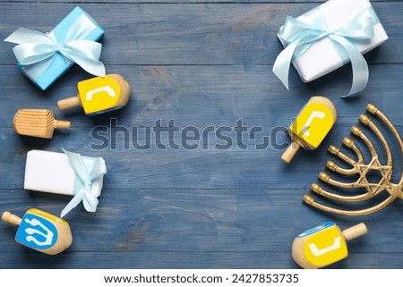 Hanukkah composition with menorah, dreidels and gift boxes on blue wooden background