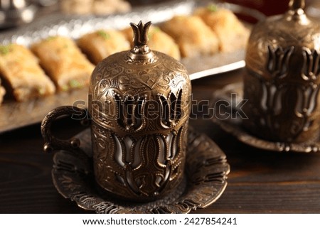 Traditional Turkish tea and fresh baklava served in vintage tea set on wooden table, closeup