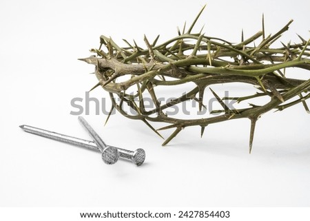 Jesus Wooden Crown of Thorns next to nails used by Catholic Christians on Good Friday Ceremony. Isolated on white background with empty blank copy text space.