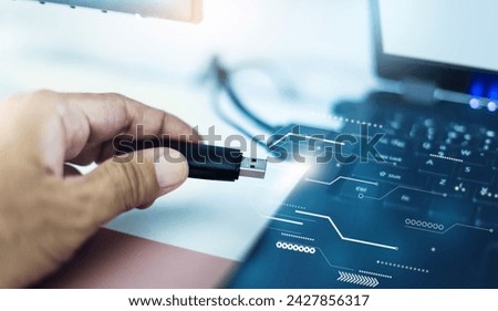 Close-up shot, hand holding of USB being connected to laptop computer with graphic symbol that data is being transfer