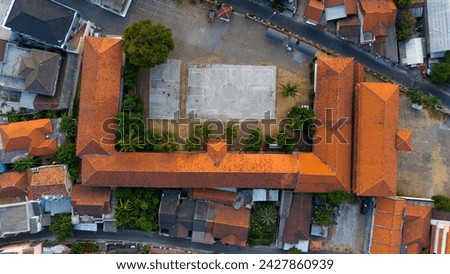 Captivating aerial view showcasing the intricate terracotta rooftops of a school complex, harmoniously integrated within a bustling residential areab