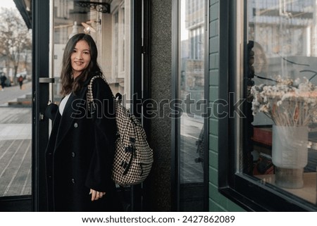 Portrait of cute Korean teenage girl walking through the city and having fun. A girl walks by a cafe with large windows. The concept of solo tourism. Horizontal photo.
