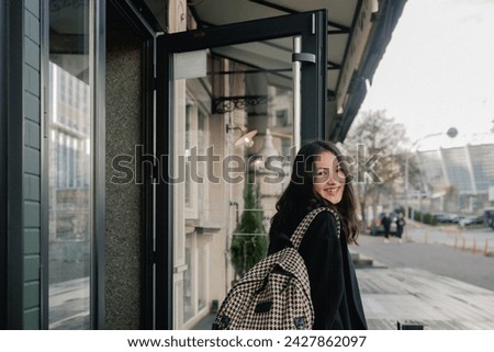 Portrait of cute Korean teenage girl walking through the city and having fun. A girl walks by a cafe with large windows. The concept of solo tourism. Horizontal photo.