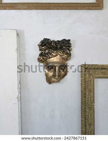 Damaged golden mask of Apollo on the wall.