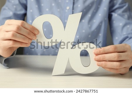 Woman holding percent sign at white wooden table, closeup
