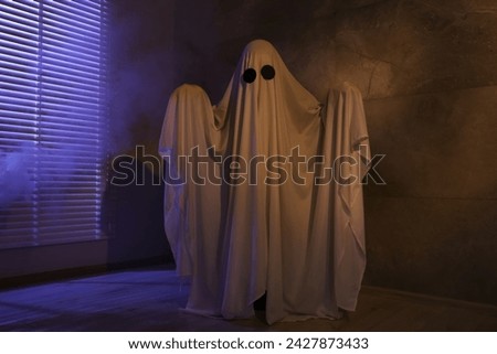 Creepy ghost. Woman covered with sheet near window in color lights