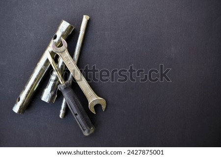 A closeup picture of metallic tools like spanner and screw driver on a black background.
