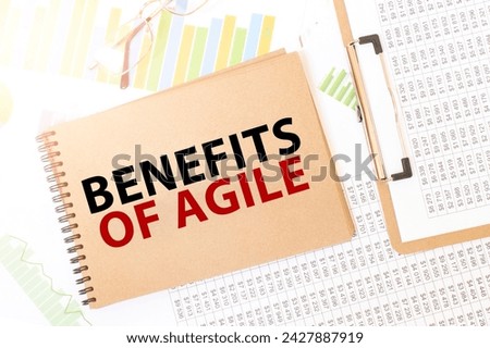 Business up graph on a sheet of craft colour Notepad with BENEFITS OF AGILE sign. Notepad on desk with financial documentation